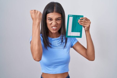 Photo for Brunette young woman holding l sign for new driver annoyed and frustrated shouting with anger, yelling crazy with anger and hand raised - Royalty Free Image