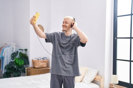 Foto de Joven hombre caucásico escuchando música y bailando en el dormitorio - Imagen libre de derechos