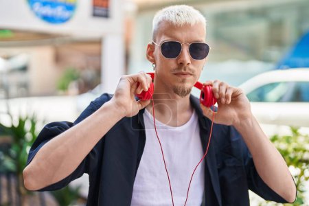 Photo for Young caucasian man wearing headphones with serious expression at street - Royalty Free Image