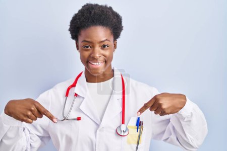 Photo for African american woman wearing doctor uniform and stethoscope looking confident with smile on face, pointing oneself with fingers proud and happy. - Royalty Free Image