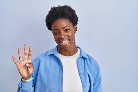 Photo for African american woman standing over blue background showing and pointing up with fingers number four while smiling confident and happy. - Royalty Free Image