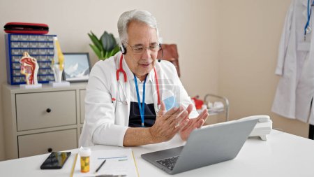 Foto de Hombre de mediana edad con médico de pelo gris haciendo cita en línea en la clínica - Imagen libre de derechos