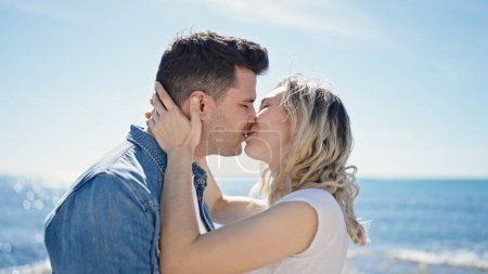 Photo for Man and woman couple standing together kissing at seaside - Royalty Free Image