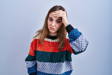 Photo for Young hispanic girl standing over blue background worried and stressed about a problem with hand on forehead, nervous and anxious for crisis - Royalty Free Image