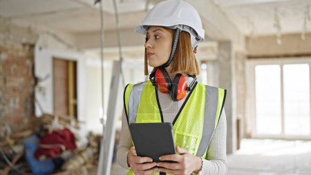 Photo for Young blonde woman architect using touchpad with serious expression at construction site - Royalty Free Image