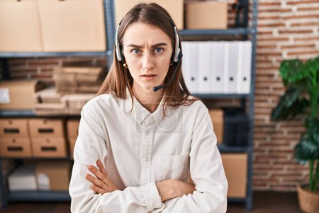 Photo for Young caucasian woman working at small business ecommerce wearing headset skeptic and nervous, disapproving expression on face with crossed arms. negative person. - Royalty Free Image