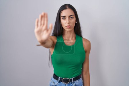 Photo for Young woman standing over isolated background doing stop sing with palm of the hand. warning expression with negative and serious gesture on the face. - Royalty Free Image