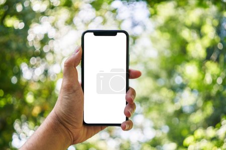 Téléchargez les photos : Homme tenant smartphone montrant écran blanc vierge au parc - en image libre de droit