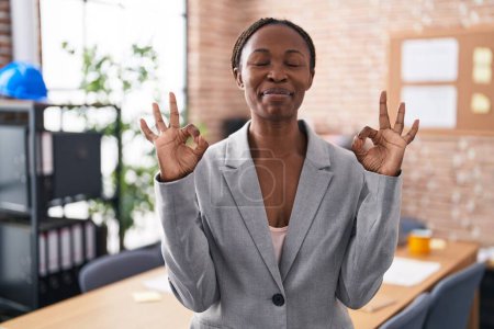 Photo for African american woman at the office relax and smiling with eyes closed doing meditation gesture with fingers. yoga concept. - Royalty Free Image