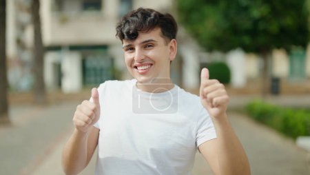 Photo for Non binary man smiling confident doing ok sign with thumbs up at park - Royalty Free Image