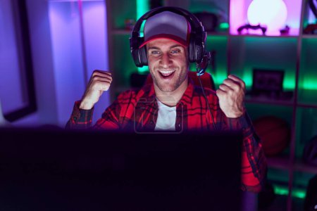 Photo for Young caucasian man playing video games screaming proud, celebrating victory and success very excited with raised arms - Royalty Free Image