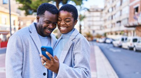 Téléchargez les photos : Homme et femme couple debout ensemble en utilisant smartphone à la rue - en image libre de droit