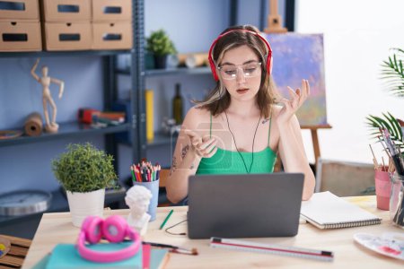Photo for Young woman artist having video call sitting on table at art studio - Royalty Free Image