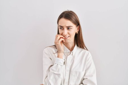 Téléchargez les photos : Young caucasian woman standing over isolated background looking stressed and nervous with hands on mouth biting nails. anxiety problem. - en image libre de droit