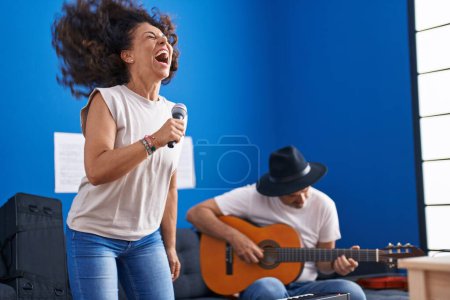 Photo for Man and woman musicians singing song playing classical guitar at music studio - Royalty Free Image