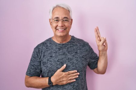 Photo for Middle age man with grey hair standing over pink background smiling swearing with hand on chest and fingers up, making a loyalty promise oath - Royalty Free Image