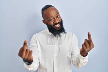 Foto de African american man standing over blue background showing middle finger doing fuck you bad expression, provocation and rude attitude. screaming excited - Imagen libre de derechos