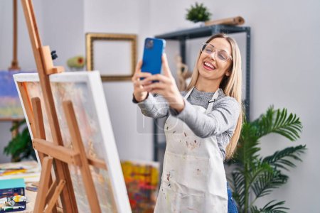 Téléchargez les photos : Jeune artiste souriante confiante faire selfie par le smartphone au studio d'art - en image libre de droit