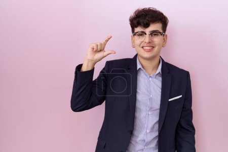 Photo for Young non binary man with beard wearing suit and tie smiling and confident gesturing with hand doing small size sign with fingers looking and the camera. measure concept. - Royalty Free Image
