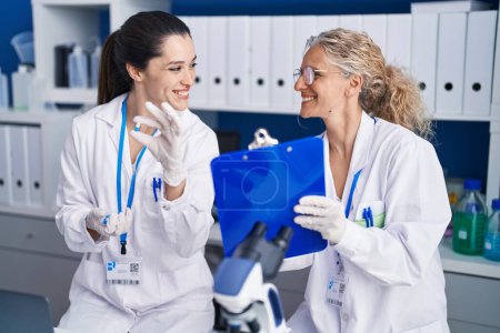 Photo for Two women scientists holding pills write on document at laboratory - Royalty Free Image