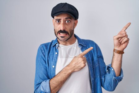 Téléchargez les photos : Homme hispanique avec la barbe debout sur fond isolé pointant de côté inquiet et nerveux avec les deux mains, préoccupé et expression surprise - en image libre de droit