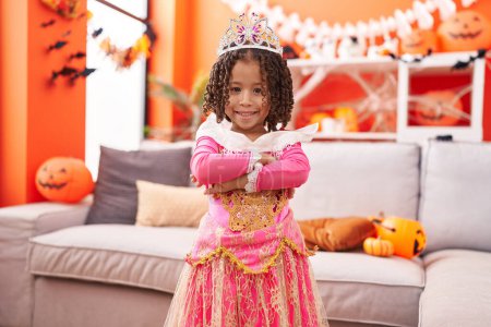 Téléchargez les photos : Africaine américaine fille portant costume de princesse debout avec les bras croisés geste à la maison - en image libre de droit