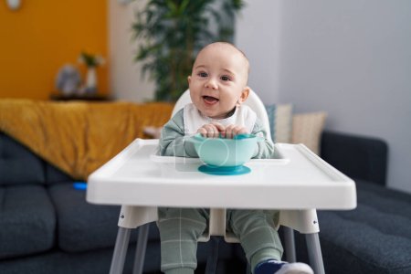 Photo for Adorable caucasian baby smiling confident sitting on highchair at home - Royalty Free Image