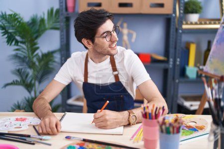 Photo for Young hispanic man artist smiling confident drawing on notebook at art studio - Royalty Free Image