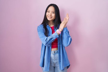 Téléchargez les photos : Jeune femme asiatique debout sur fond rose applaudissant heureux et joyeux, souriant mains fières ensemble - en image libre de droit
