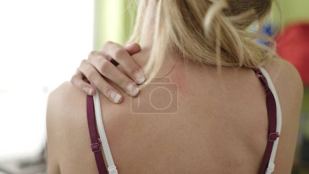 Téléchargez les photos : Jeune femme blonde massant le dos pour une blessure au centre sportif - en image libre de droit