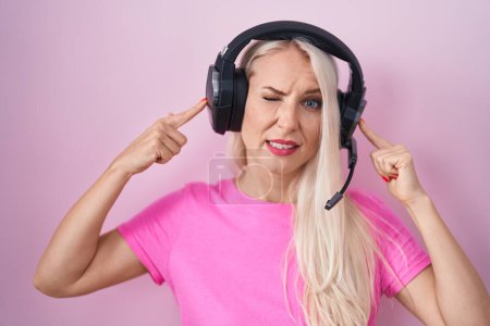 Téléchargez les photos : Femme caucasienne écoutant de la musique à l'aide d'écouteurs couvrant les oreilles avec des doigts avec une expression agacée pour le bruit de la musique forte. concept sourd. - en image libre de droit