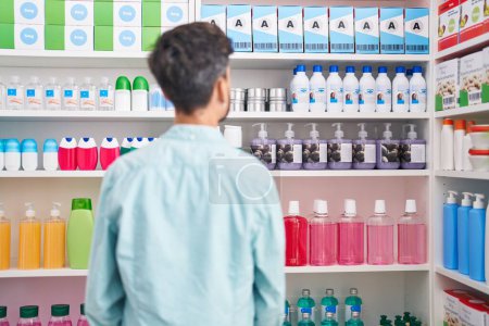 Téléchargez les photos : Jeune homme hispanique client regardant étagères à la pharmacie - en image libre de droit
