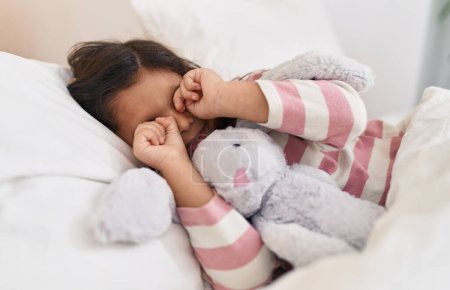 Téléchargez les photos : Adorable hispanique fille couchée sur le lit se réveillant dans la chambre - en image libre de droit