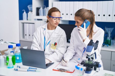 Photo for Two women scientists talking on the smartphone working at laboratory - Royalty Free Image