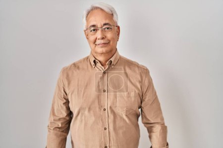 Photo for Hispanic senior man wearing glasses relaxed with serious expression on face. simple and natural looking at the camera. - Royalty Free Image