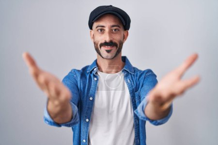 Téléchargez les photos : Homme hispanique avec barbe debout sur fond isolé souriant joyeuse offrant des mains donnant assistance et acceptation. - en image libre de droit