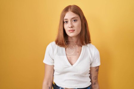 Photo for Young redhead woman standing over yellow background looking sleepy and tired, exhausted for fatigue and hangover, lazy eyes in the morning. - Royalty Free Image