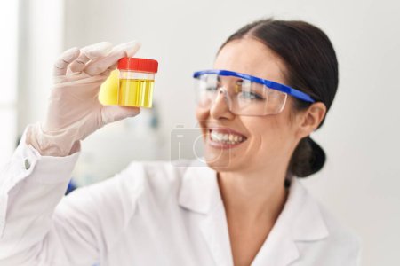 Téléchargez les photos : Jeune belle femme hispanique scientifique tenant un tube à essai d'urine au laboratoire - en image libre de droit