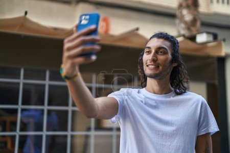 Téléchargez les photos : Young hispanic man smiling confident making selfie by the smartphone at coffee shop terrace - en image libre de droit