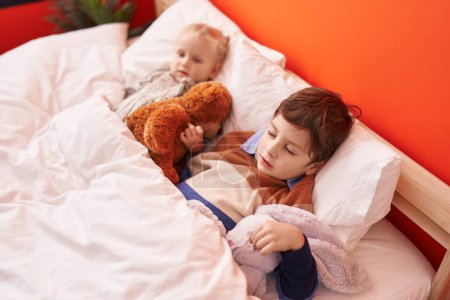 Photo for Adorable boy and girl hugging teddy bear sleeping on bed at bedroom - Royalty Free Image
