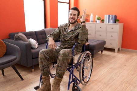 Téléchargez les photos : Jeune soldat hispanique homme blessé assis sur un fauteuil roulant faire ok signe avec les doigts, sourire geste amical excellent symbole - en image libre de droit