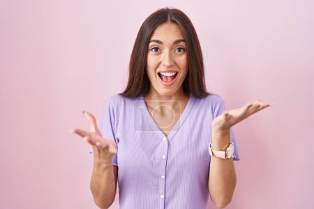 Photo for Young hispanic woman with long hair standing over pink background celebrating crazy and amazed for success with arms raised and open eyes screaming excited. winner concept - Royalty Free Image