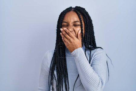 Photo for African american woman standing over blue background bored yawning tired covering mouth with hand. restless and sleepiness. - Royalty Free Image