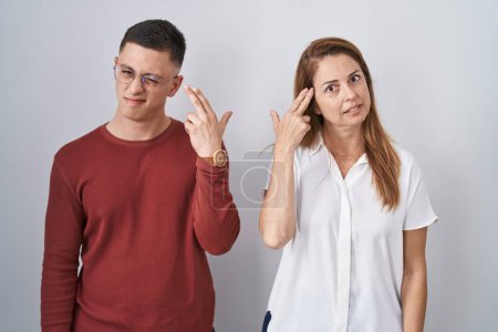 Photo for Mother and son standing together over isolated background shooting and killing oneself pointing hand and fingers to head like gun, suicide gesture. - Royalty Free Image