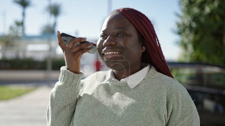 Photo for African woman with braided hair listening voice message with smartphone at street - Royalty Free Image