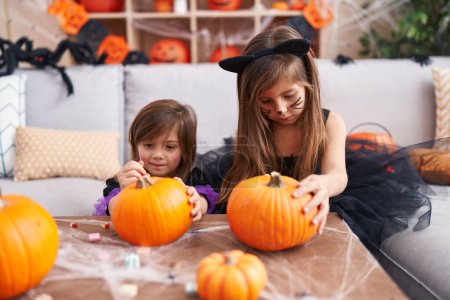 Photo for Adorable girls having halloween party drawing on pumpkin at home - Royalty Free Image