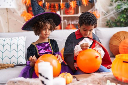Photo for Adorable african american boy and girl having halloween party drawing on balloon at home - Royalty Free Image