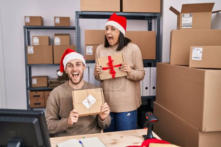 Téléchargez les photos : Deux jeunes gens travaillant dans le commerce électronique des petites entreprises à Noël célébrant fou et étonné pour le succès avec les yeux ouverts hurlant excité. - en image libre de droit
