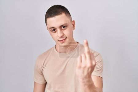 Foto de Young man standing over isolated background showing middle finger, impolite and rude fuck off expression - Imagen libre de derechos