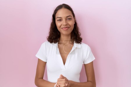 Photo for Young hispanic woman wearing casual white t shirt with hands together and crossed fingers smiling relaxed and cheerful. success and optimistic - Royalty Free Image